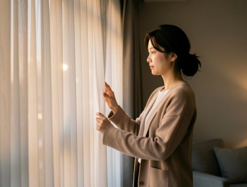 Une actrice coréenne pensive ferme doucement des rideaux dans un intérieur contemporain baigné de lumière chaleureuse.